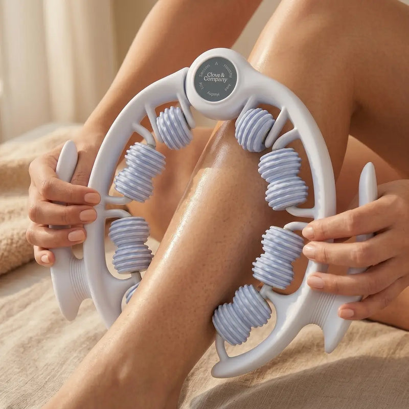 A close-up of a person using a white and light blue leg massager roller on their leg, held in place by hands.