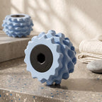 A light blue textured roller with a black center hole stands on a speckled stone surface.
